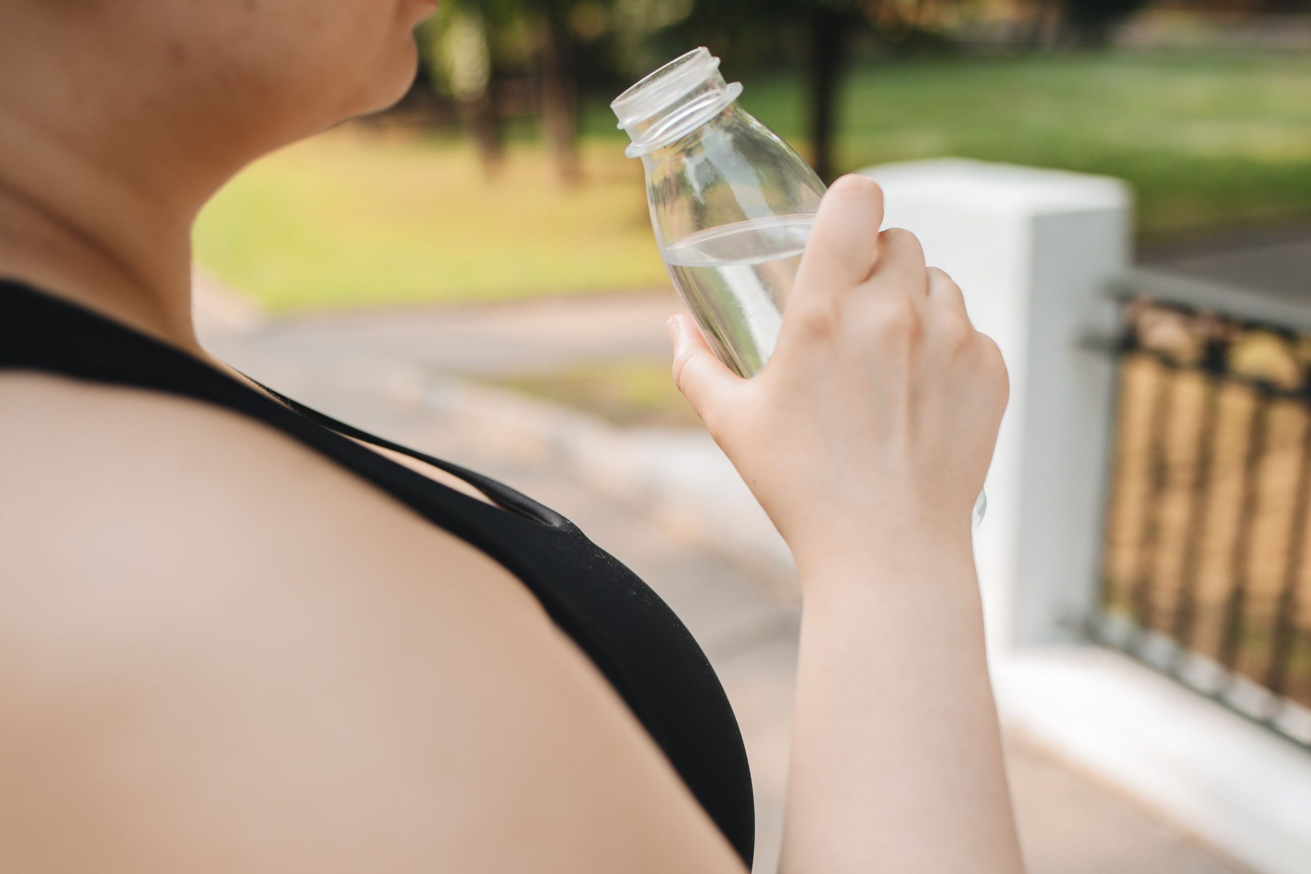 A woman drinking cold water from a clear bottle after a panic attack