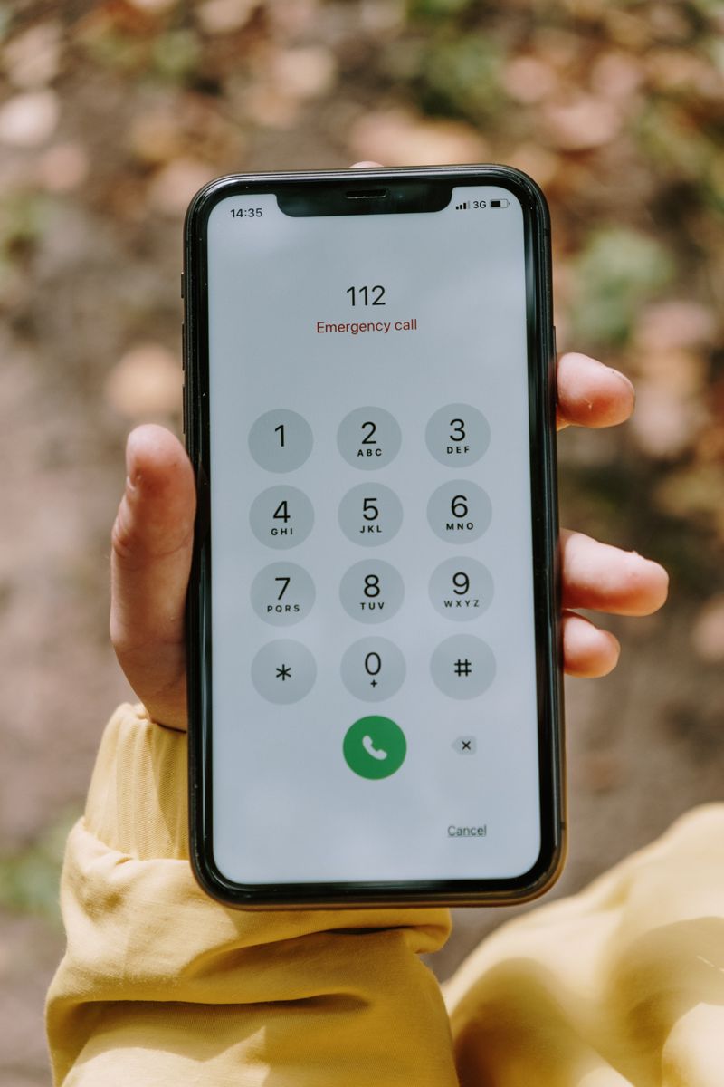 Hand holding a phone dialing 112, India's emergency number
