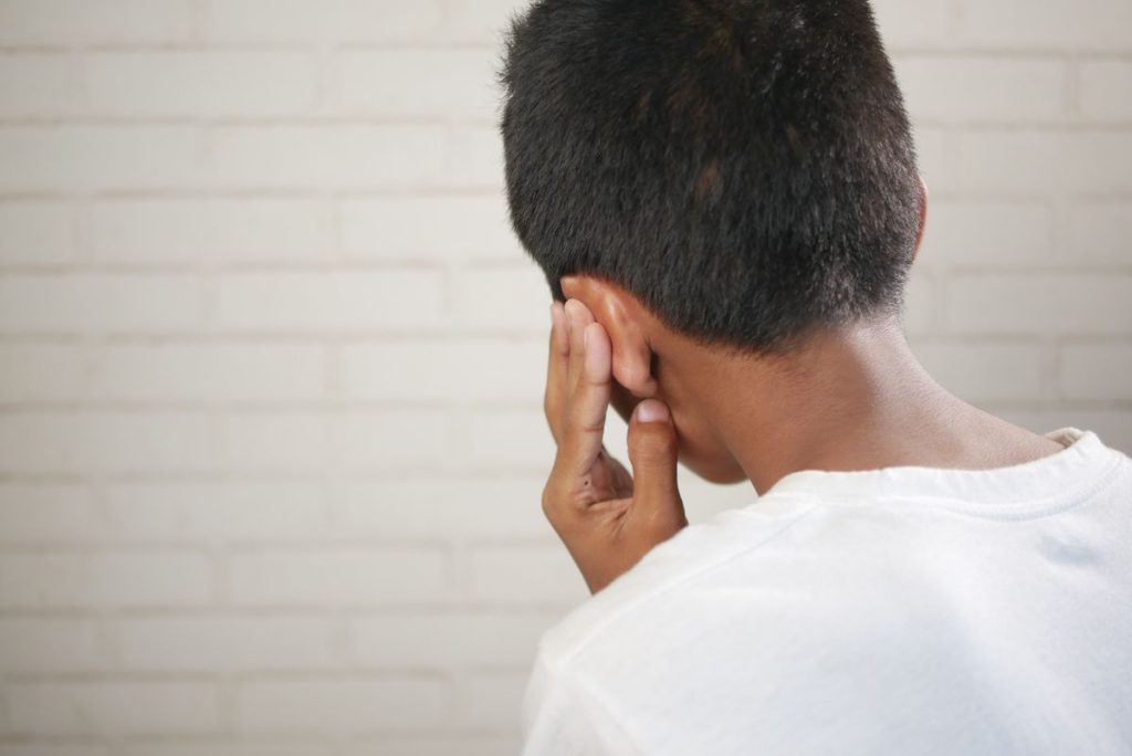 Child holding a hand over their ear in discomfort