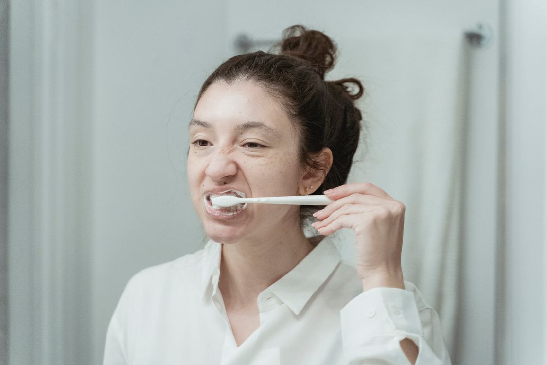 Person brushing teeth gently at a bathroom sink