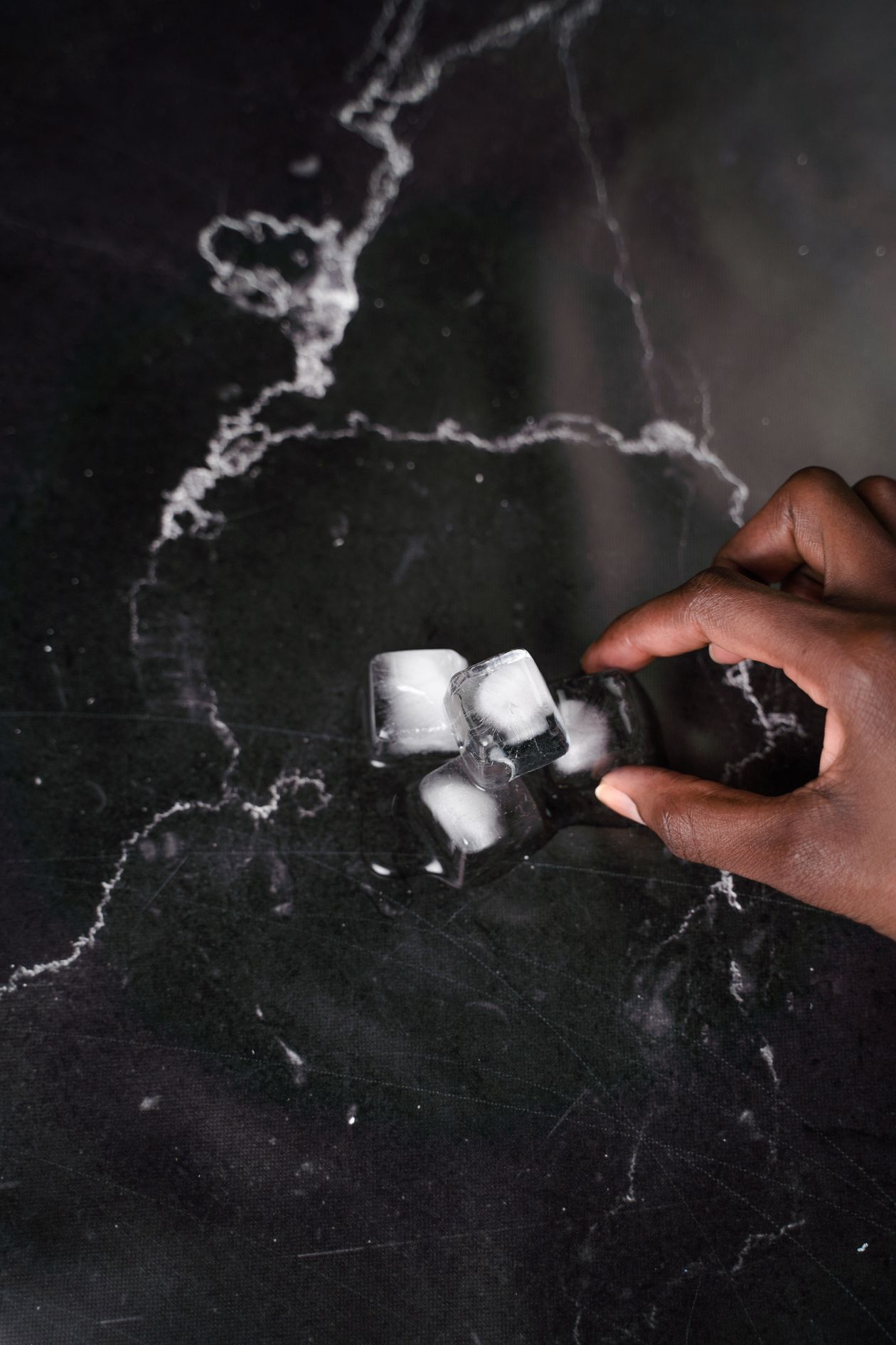 Hand holding ice cubes — cold reduces swelling so the ring can slide over the knuckle