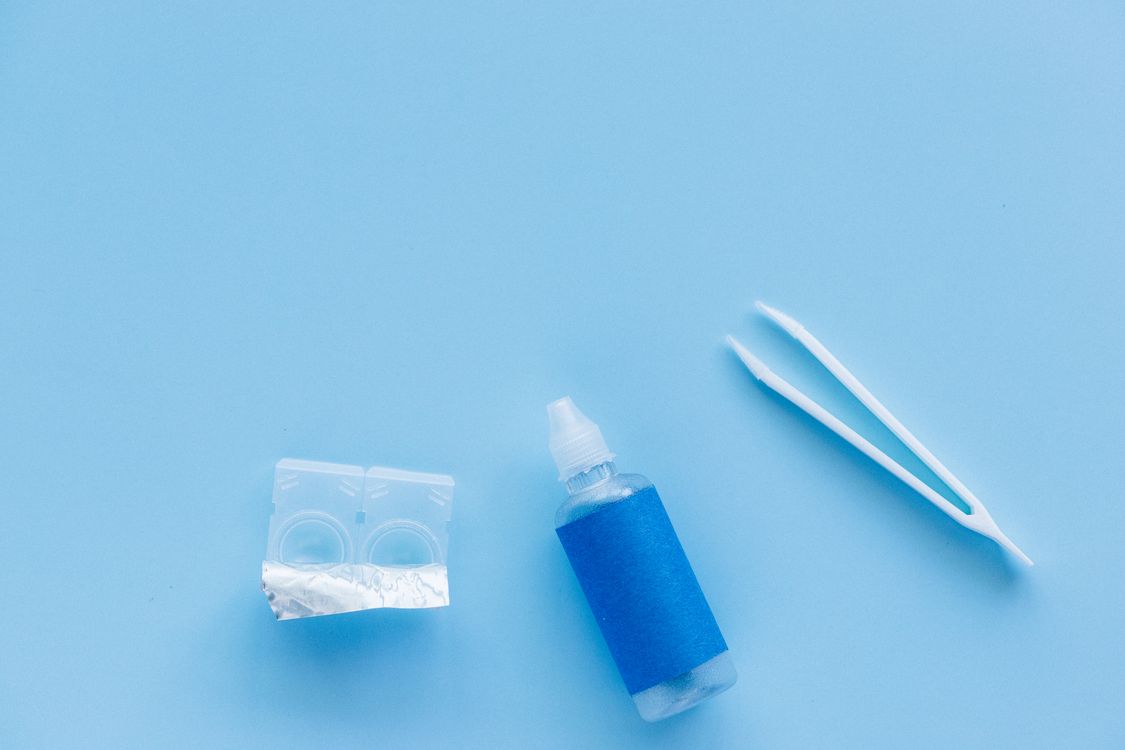 Contact lens case, solution bottle and tweezers in a flat lay