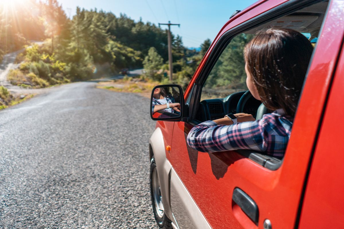 Car passenger looking out at the road ahead through an open window