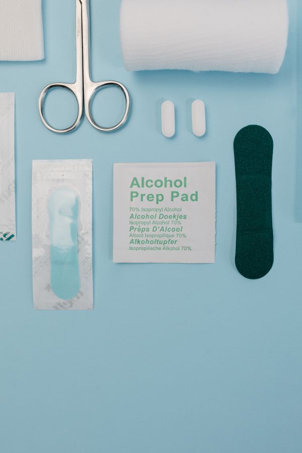 First aid supplies: scissors, bandage roll, alcohol prep pad and pills