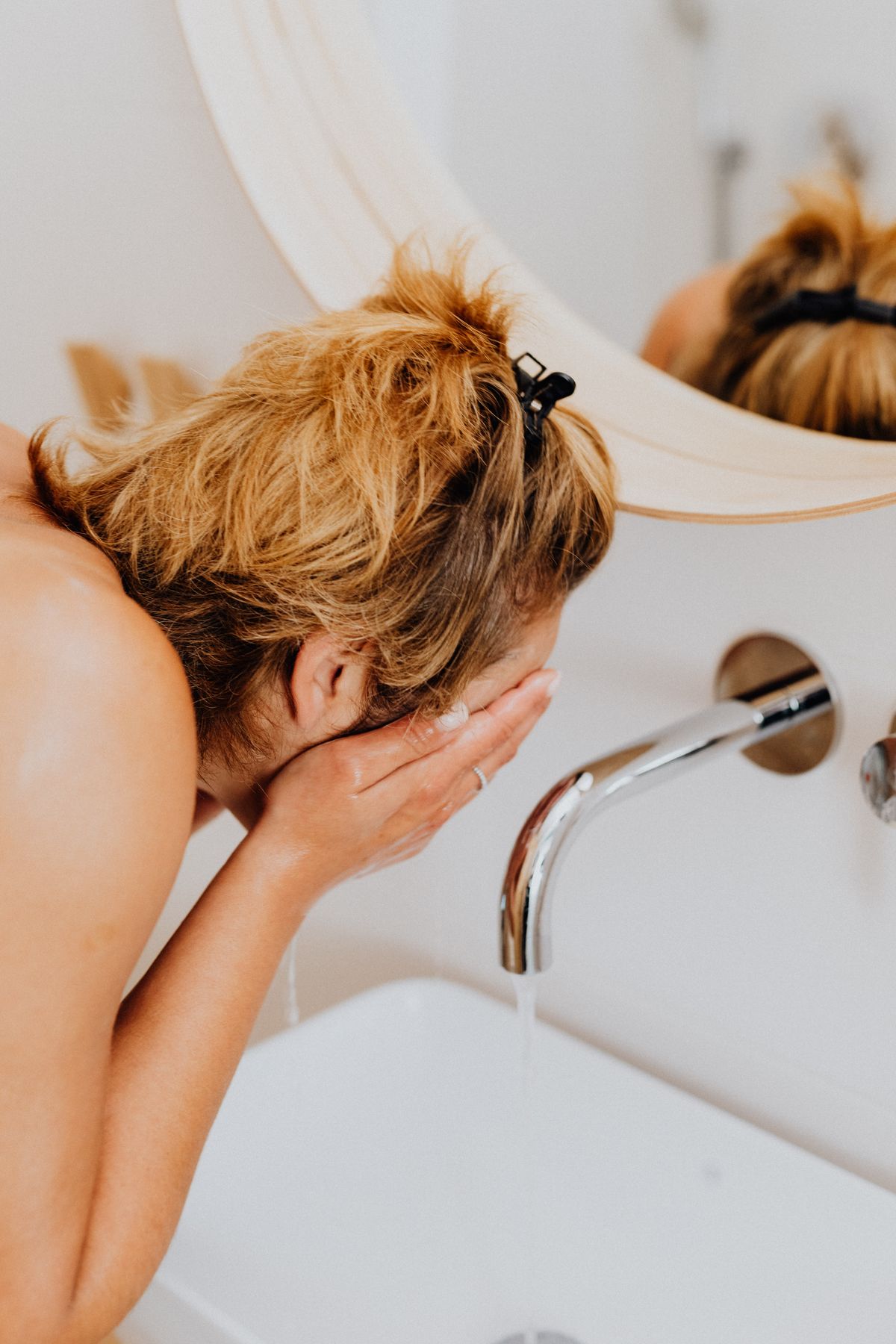 Woman splashing cold water on her face in the morning