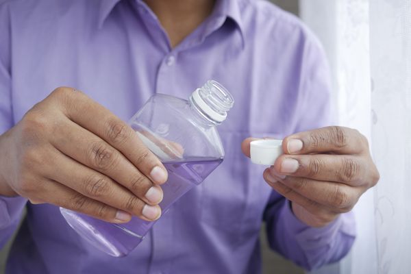 Person preparing a mouthwash-style gargle — warm salt water gargling soothes a sore throat