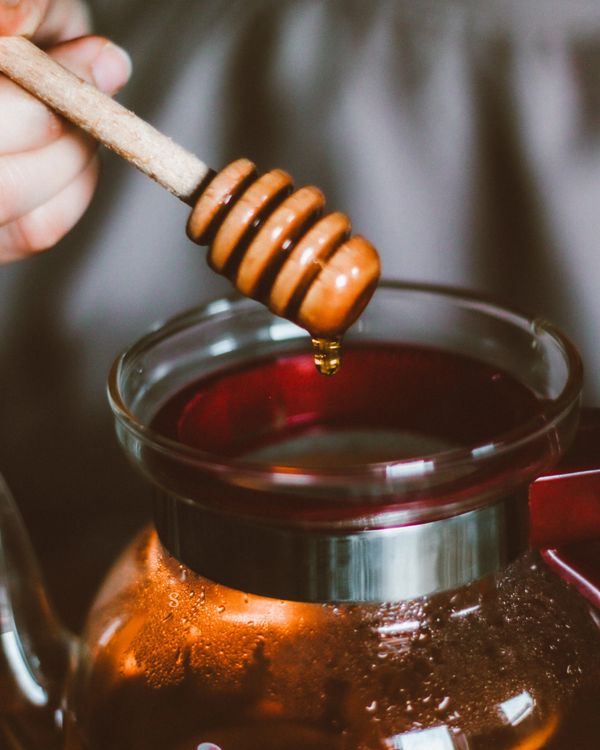 Honey dripping into a warm teapot — honey and warm drinks soothe a sore throat