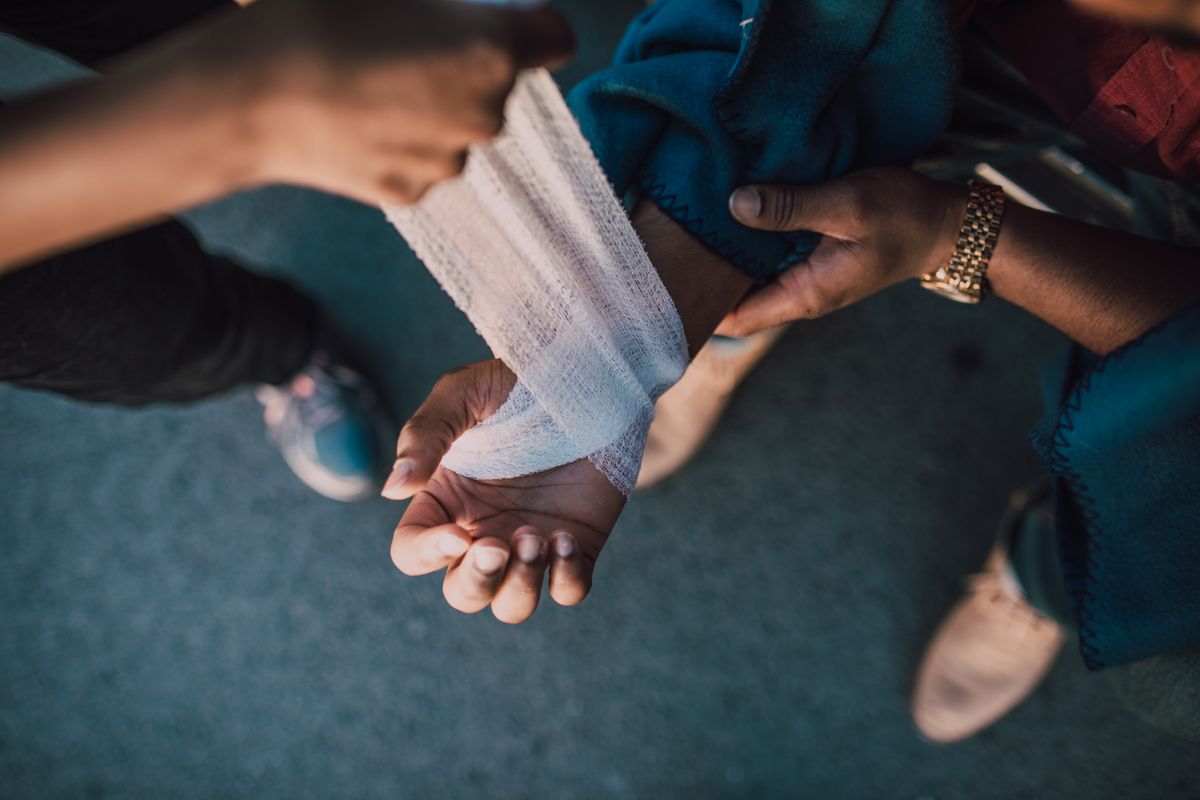 Wrist being wrapped with a gauze bandage after wound cleaning